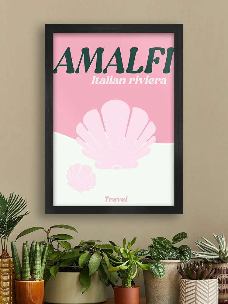 Framed poster with 'Amalfi Italian Riviera' design on a wall with plants below.
