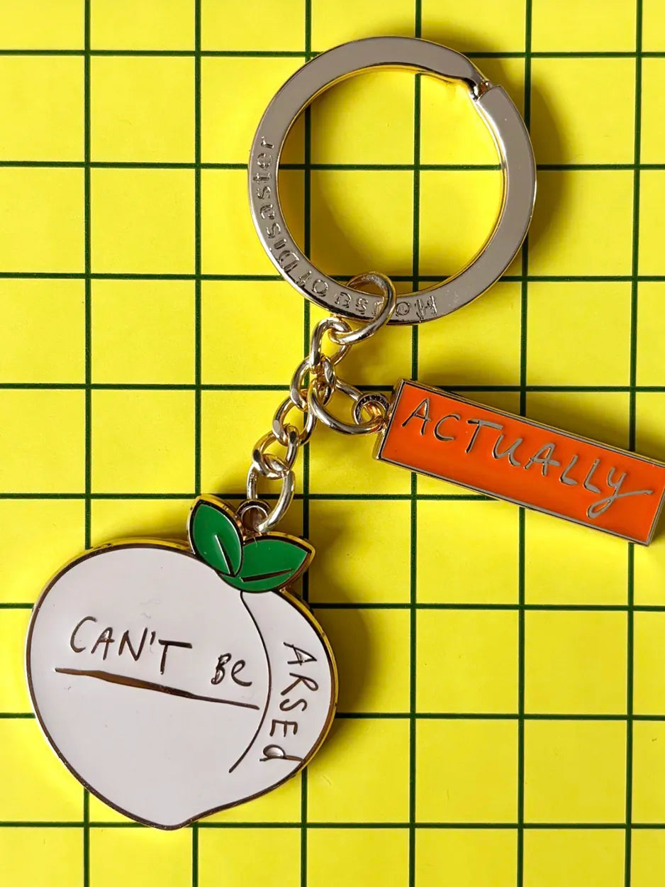 This cute metal keyring is finished in enamel. It features the slogan 'Can't be arsed actually'
