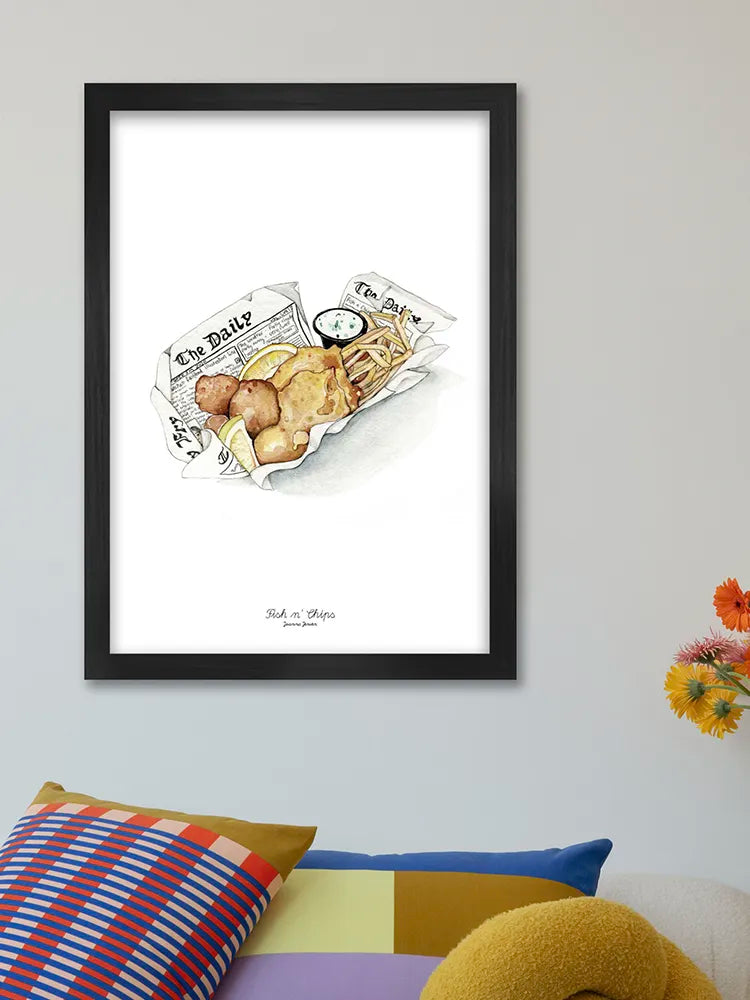 Framed artwork of a newspaper with food illustrations on a wall above a colorful sofa.