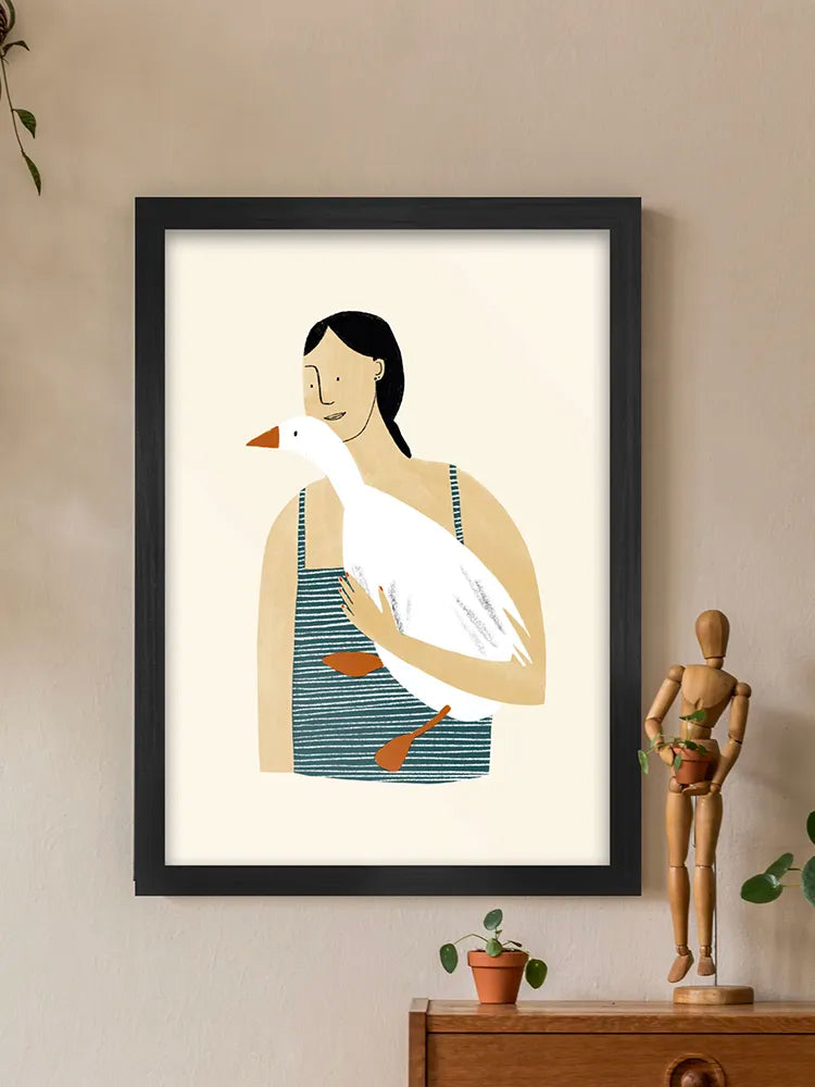 Framed artwork of a woman holding a goose on a beige wall with a wooden cabinet and plant.
