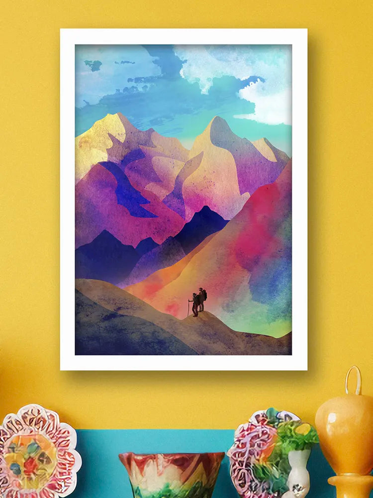 Framed colorful mountain landscape painting on a yellow wall with decorative items below.