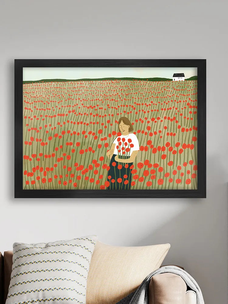 Framed artwork of a woman in a field of red flowers on a wall above a sofa.