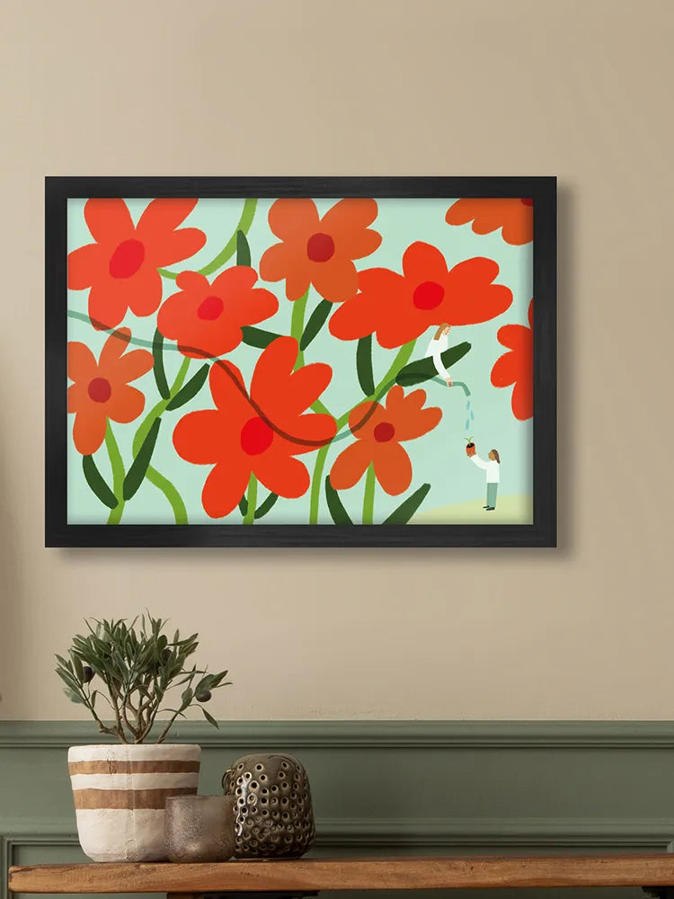 Framed artwork with red flowers on a beige wall above a wooden shelf with decorative items.